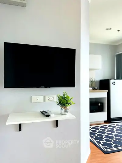 Modern living room with wall-mounted TV and stylish kitchen area