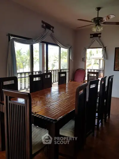 Spacious dining room with elegant wooden table and chairs, featuring large windows with scenic views.
