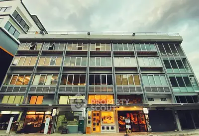 Modern multi-story building with large windows and retail space on ground floor, ideal for urban living.