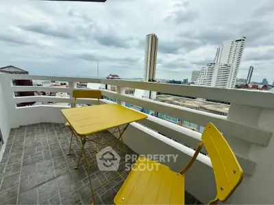 Charming balcony with city and sea views, featuring vibrant yellow outdoor furniture.