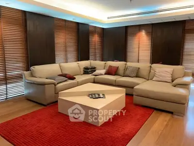 Luxurious living room with modern sectional sofa and elegant wooden blinds.
