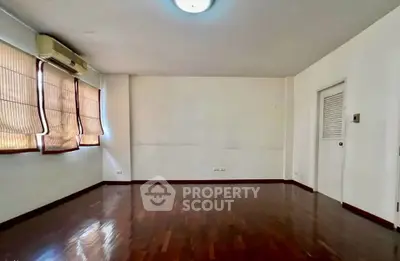 Spacious empty room with wooden flooring and natural light, ideal for customization.