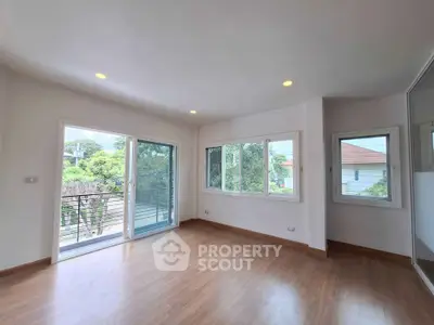 Spacious living room with large windows and balcony access, offering abundant natural light and serene views.