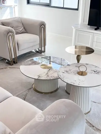 Luxurious modern living room with elegant marble coffee tables and plush seating.