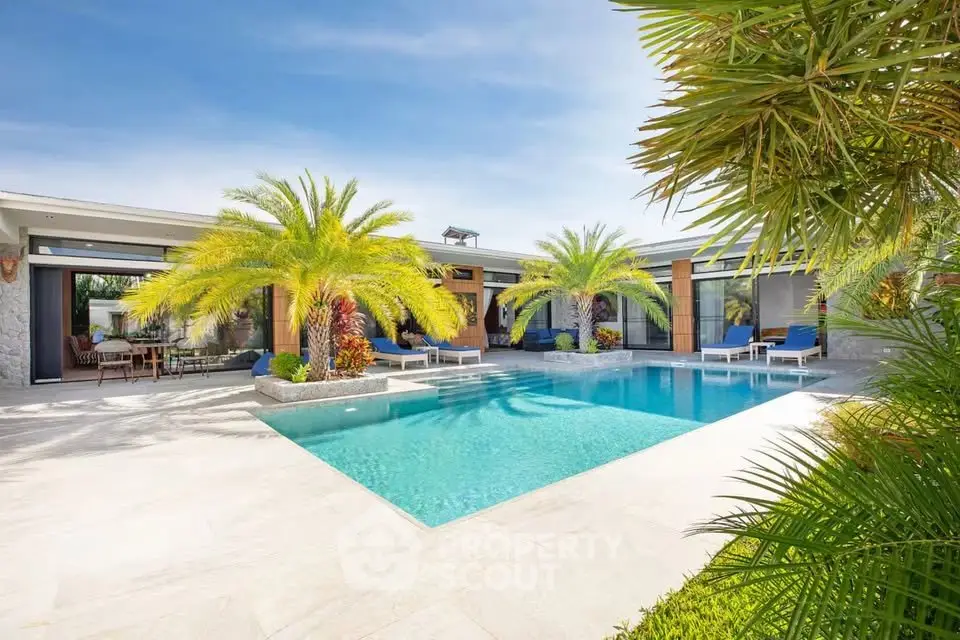 Luxurious modern villa with stunning pool and lush palm trees, perfect for tropical living.