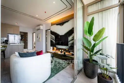Modern living room with open kitchen and stylish decor, featuring large windows and indoor plants.