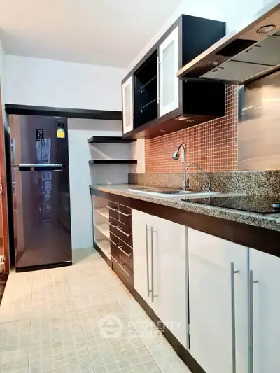 Modern kitchen with sleek cabinetry and granite countertops in a stylish apartment.