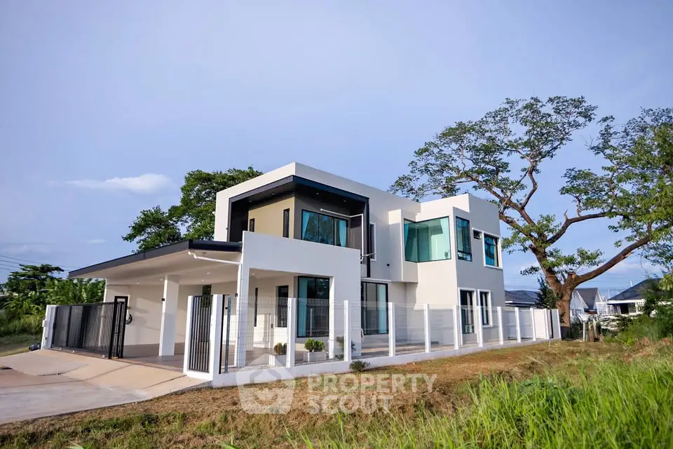 Modern two-story house with sleek design and large windows, surrounded by lush greenery.