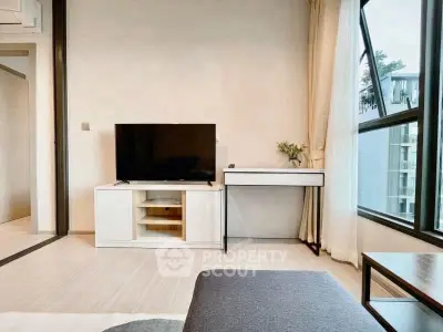 Modern living room with sleek TV setup and large windows offering natural light.