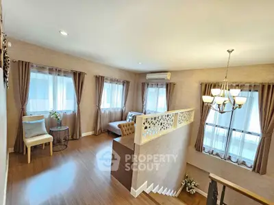 Elegant living room with stylish decor and natural light, featuring a cozy seating area and modern chandelier.