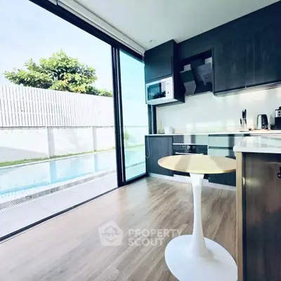Modern kitchen with pool view and sleek appliances, featuring open layout and stylish design.