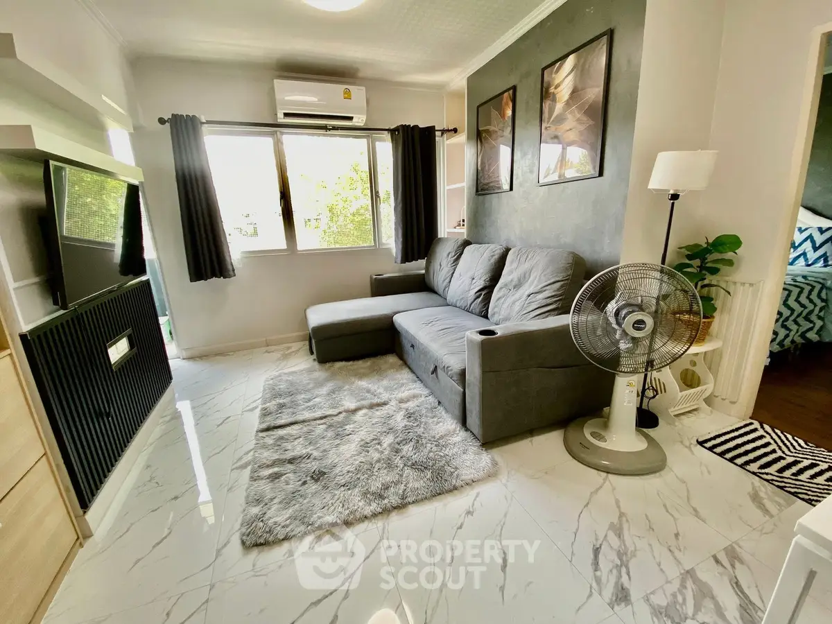 Modern living room with sleek design, featuring a cozy gray sofa, stylish decor, and natural light from large window.