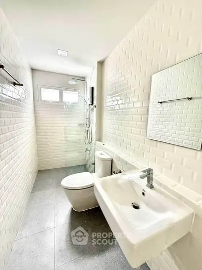 Modern bathroom with sleek white tiles and glass shower enclosure