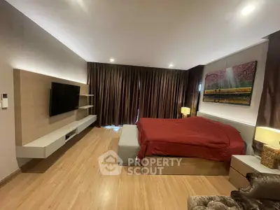 Spacious bedroom with modern decor and large TV, perfect for relaxation.