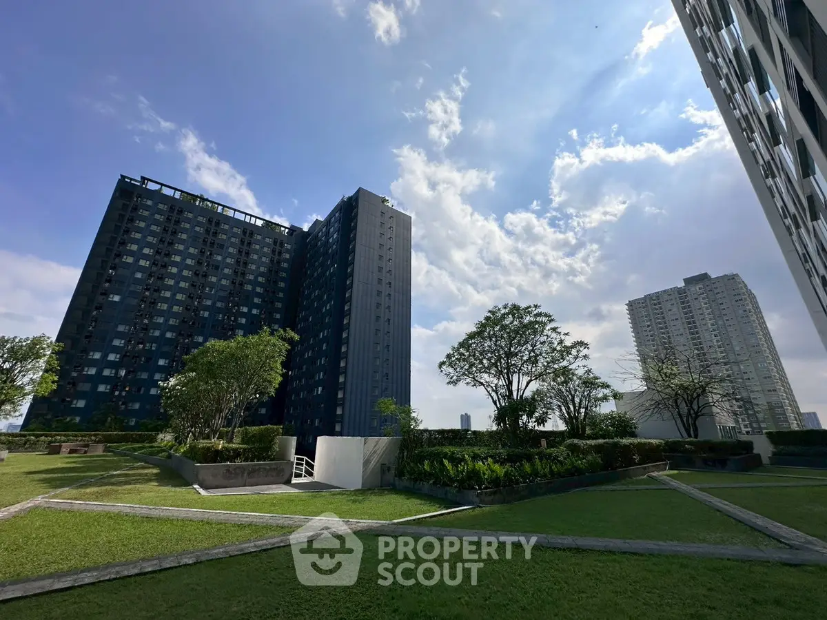 Stunning modern high-rise buildings with lush landscaped gardens and clear blue sky.