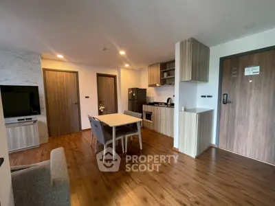 Modern open-plan living room with kitchen, wooden flooring, and stylish furniture in a cozy apartment.