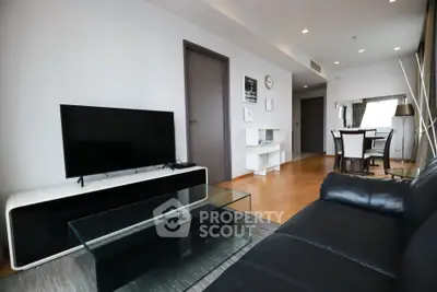 Spacious modern living room with sleek furniture and large TV, perfect for relaxation and entertainment.