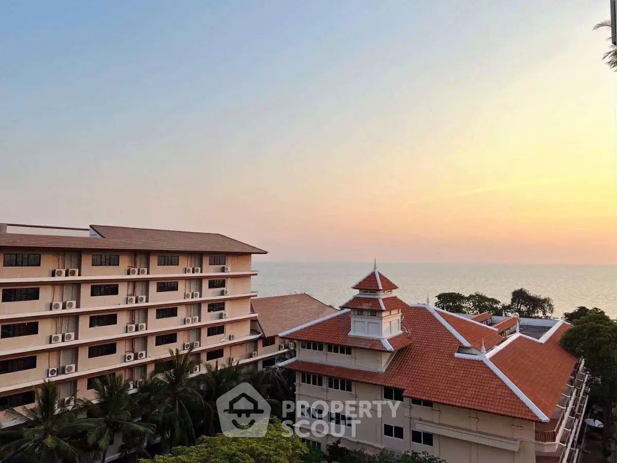Stunning coastal view from a high-rise building with red-tiled roofs at sunset.