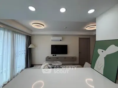 Modern living room with stylish lighting and wall art, featuring a sleek TV setup and large windows.