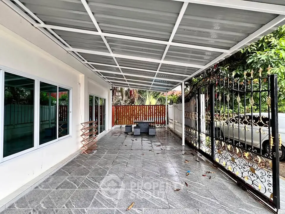 Spacious covered patio with modern design and elegant iron gate, perfect for outdoor relaxation.