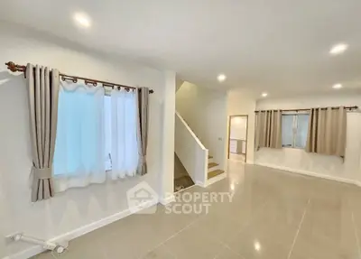 Spacious modern living room with elegant staircase and large windows in a contemporary home.