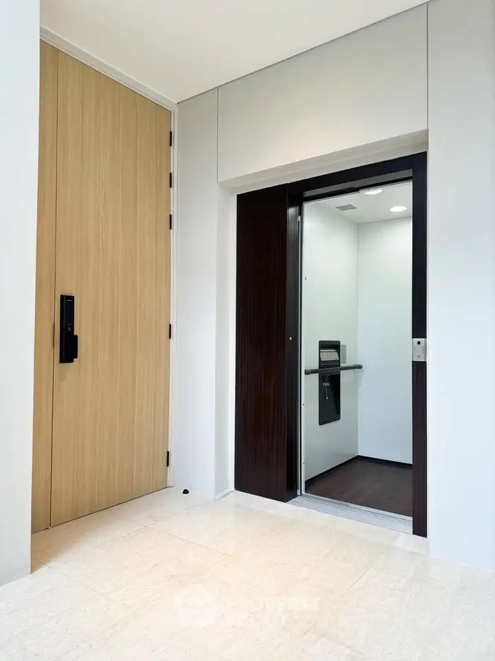 Modern home entrance with sleek elevator and wooden door