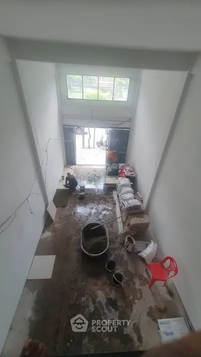 Spacious interior under renovation with high ceiling and large window, ideal for customization.