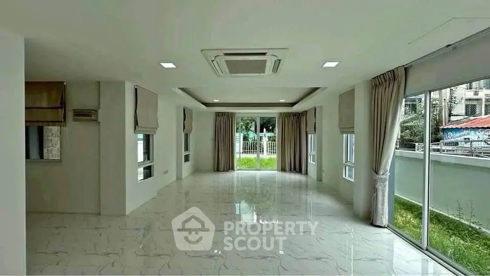 Spacious and bright living room with large windows and garden view.