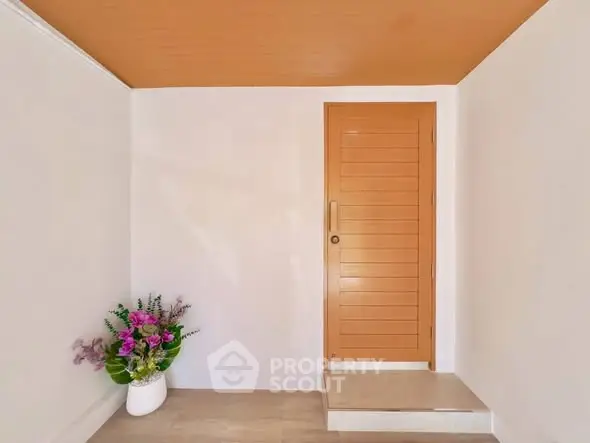 Minimalist entrance with wooden door and floral decor, perfect for modern homes.