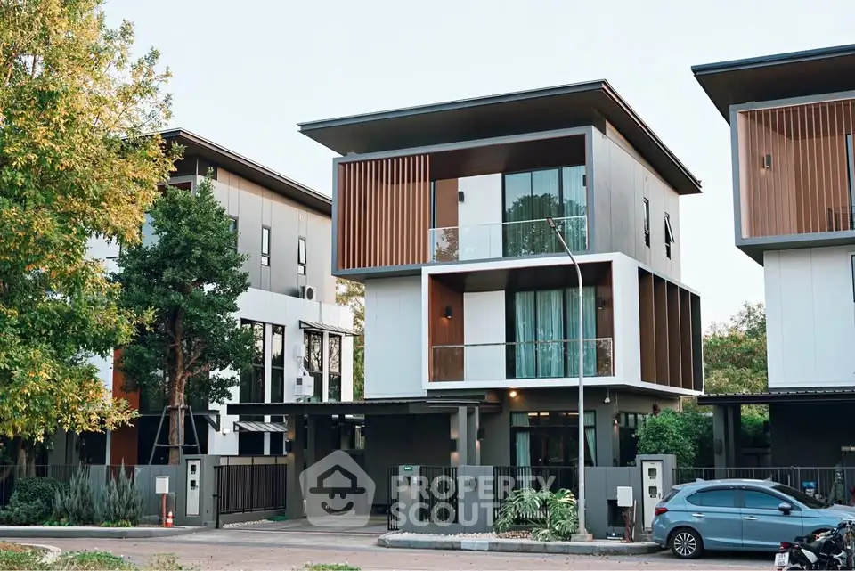 Modern three-story house with sleek design and large windows in a suburban neighborhood.