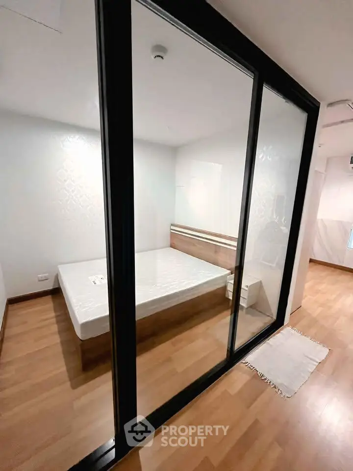 Modern bedroom with glass partition and wooden flooring in a stylish apartment.