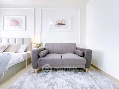 Modern bedroom with stylish gray sofa and plush rug, perfect for relaxation and comfort.