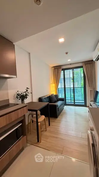 Modern living room with open kitchen and balcony view in a stylish apartment.