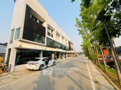Modern multi-story building with street view and parked car, ideal for commercial or residential use.
