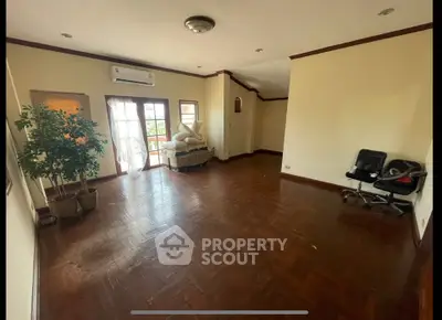 Spacious living room with wooden flooring and natural light, featuring a balcony view.