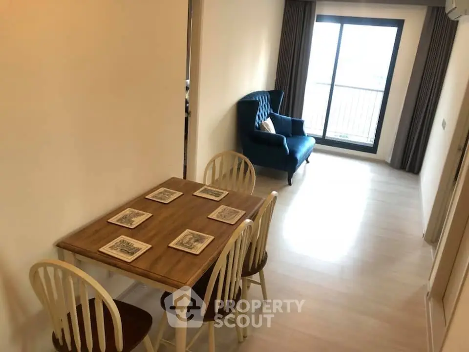 Cozy dining area with wooden table and chairs, leading to a bright living room with balcony view.