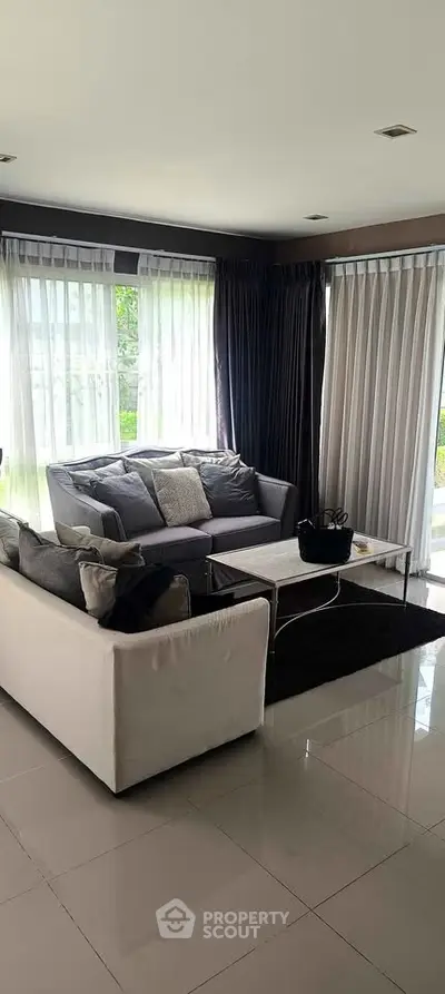 Elegant living room with modern furniture and large windows offering natural light.