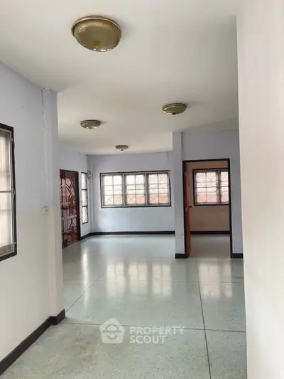 Spacious empty living room with large windows and natural light in a modern home.