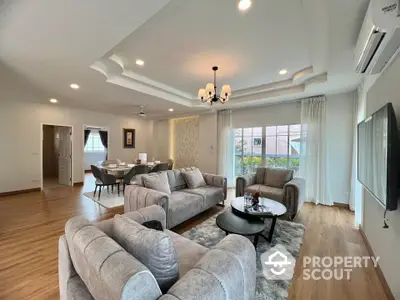 Spacious living room with elegant gray sofas, wooden flooring, and modern chandelier, perfect for family gatherings.