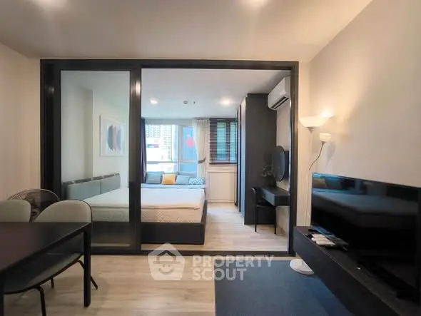 Modern studio apartment with glass partition, cozy bedroom, and stylish living area.