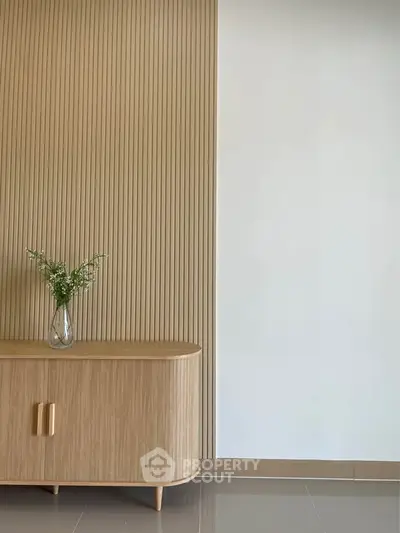 Stylish minimalist interior with wooden cabinet and decorative vase, perfect for modern living spaces.