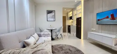 Modern living room with cozy seating and stylish decor, open layout to kitchen area.