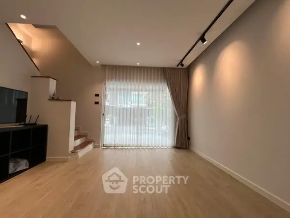 Spacious modern living room with wooden flooring and large window