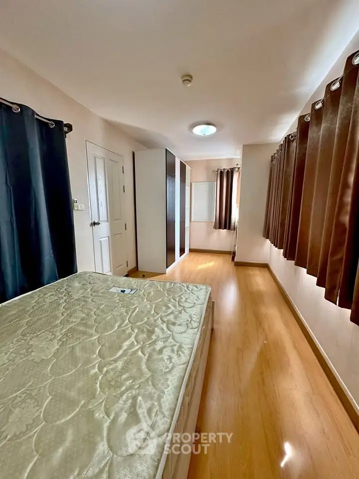 Spacious bedroom with wooden flooring and ample natural light