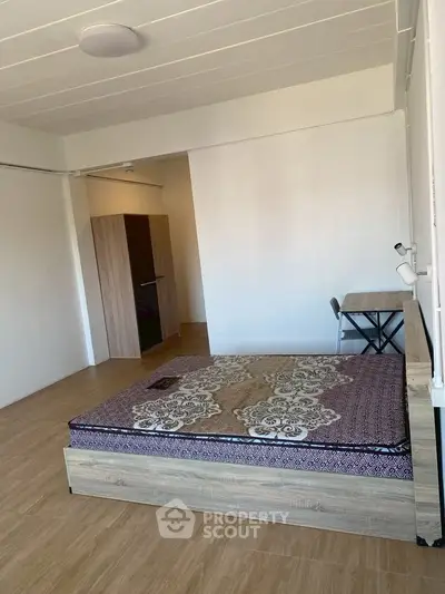 Spacious bedroom with wooden flooring and modern furniture, ideal for comfortable living.
