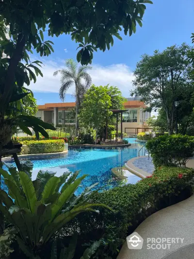 Luxurious tropical pool surrounded by lush greenery in a modern residential complex.