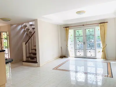 Spacious living room with large windows and elegant staircase