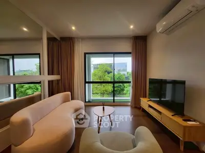 Stylish living room with modern furniture and large window offering lush green views.