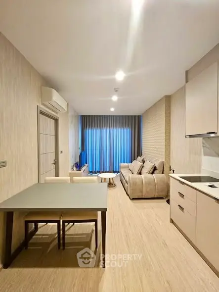 Modern open-layout living room with kitchen, featuring sleek furniture and ambient lighting.