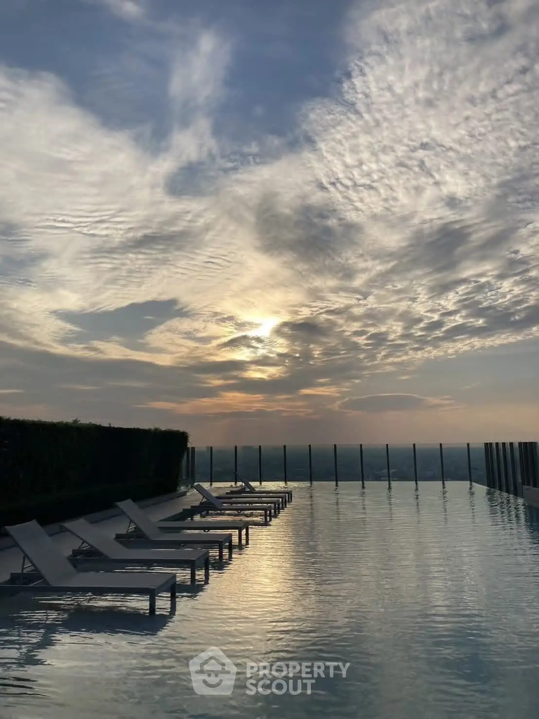 Stunning rooftop infinity pool with breathtaking sunset view and luxurious lounge chairs.